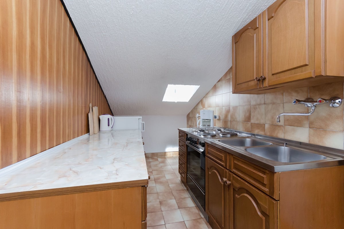 A kitchen with wooden cabinets, a marble countertop, a built-in oven, and a double sink.
