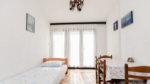 Una camera da letto con due letti singoli, un tavolo da pranzo con sedie, un lampadario e un'ampia finestra con tende.