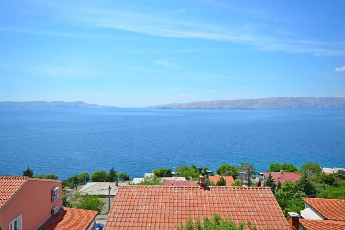A coastal residential area with red-tiled roofs and a view of the sea.