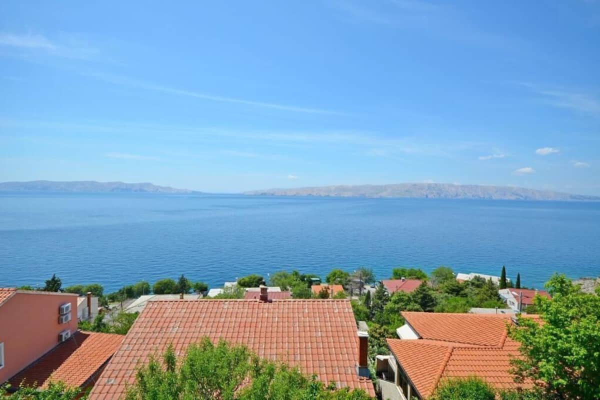 A coastal residential area with red-tiled roofs and houses overlooking a large body of water.