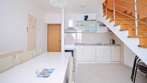 A modern kitchen with white cabinets, a built-in oven, and a stainless steel range hood. - Apartments Ivanka (Senj)