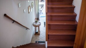 A wooden staircase with a handrail, leading to a room with a tiled floor and a small table with a plant. - House Predrag (Supetarska Draga)