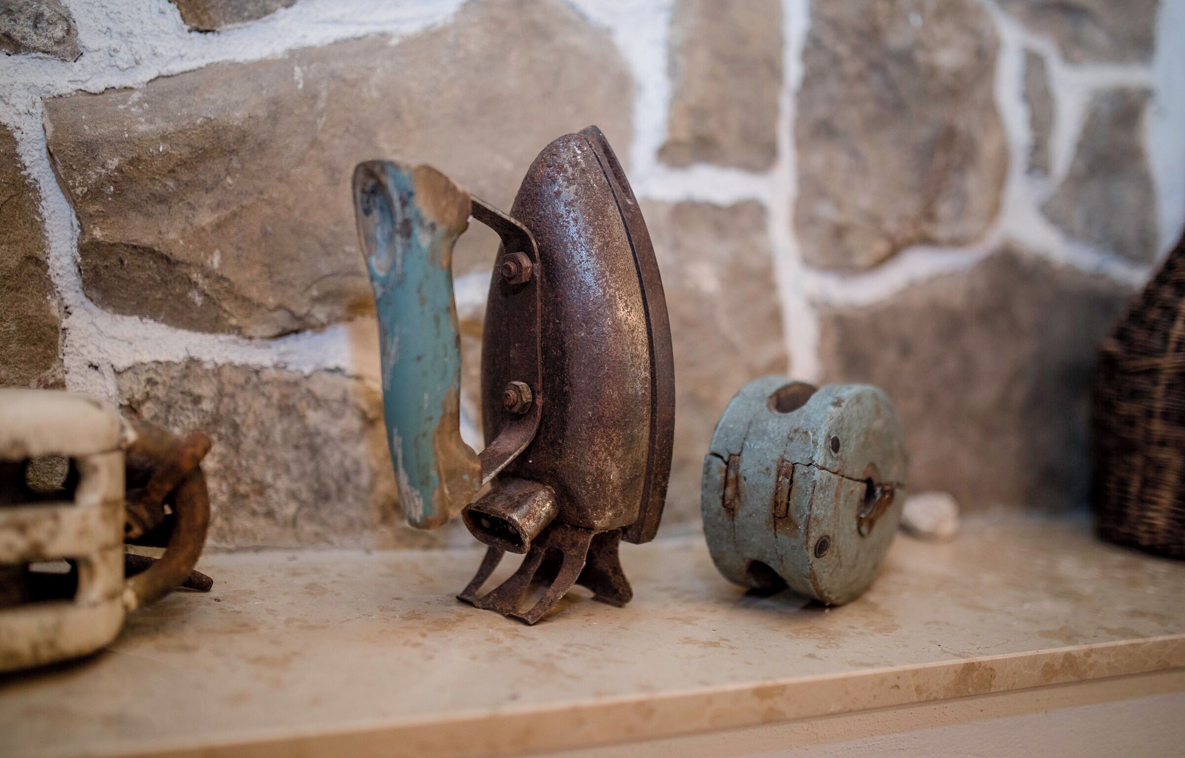 A stone wall with a shelf displaying various metal objects.