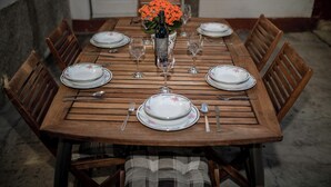A wooden dining table set for six with floral plates, wine glasses, and a bottle of wine. - House Predrag (Supetarska Draga)