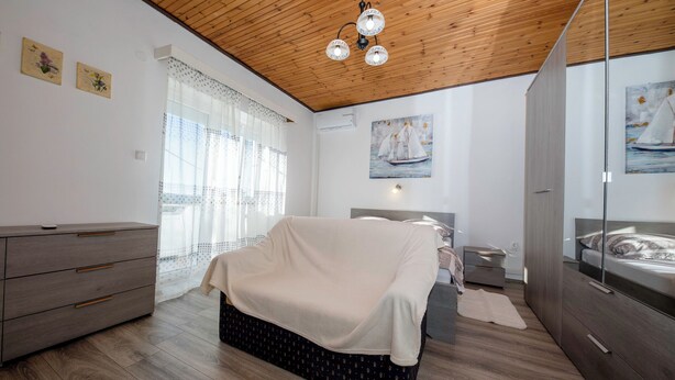A bedroom with a bed covered in a blanket, a dresser, a bedside table, and a wardrobe. - House Predrag (Supetarska Draga)