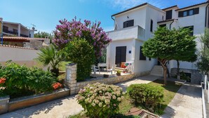 A residential area with modern houses, a paved courtyard, and flowering plants. - Apartments Dragica (Stinjan)