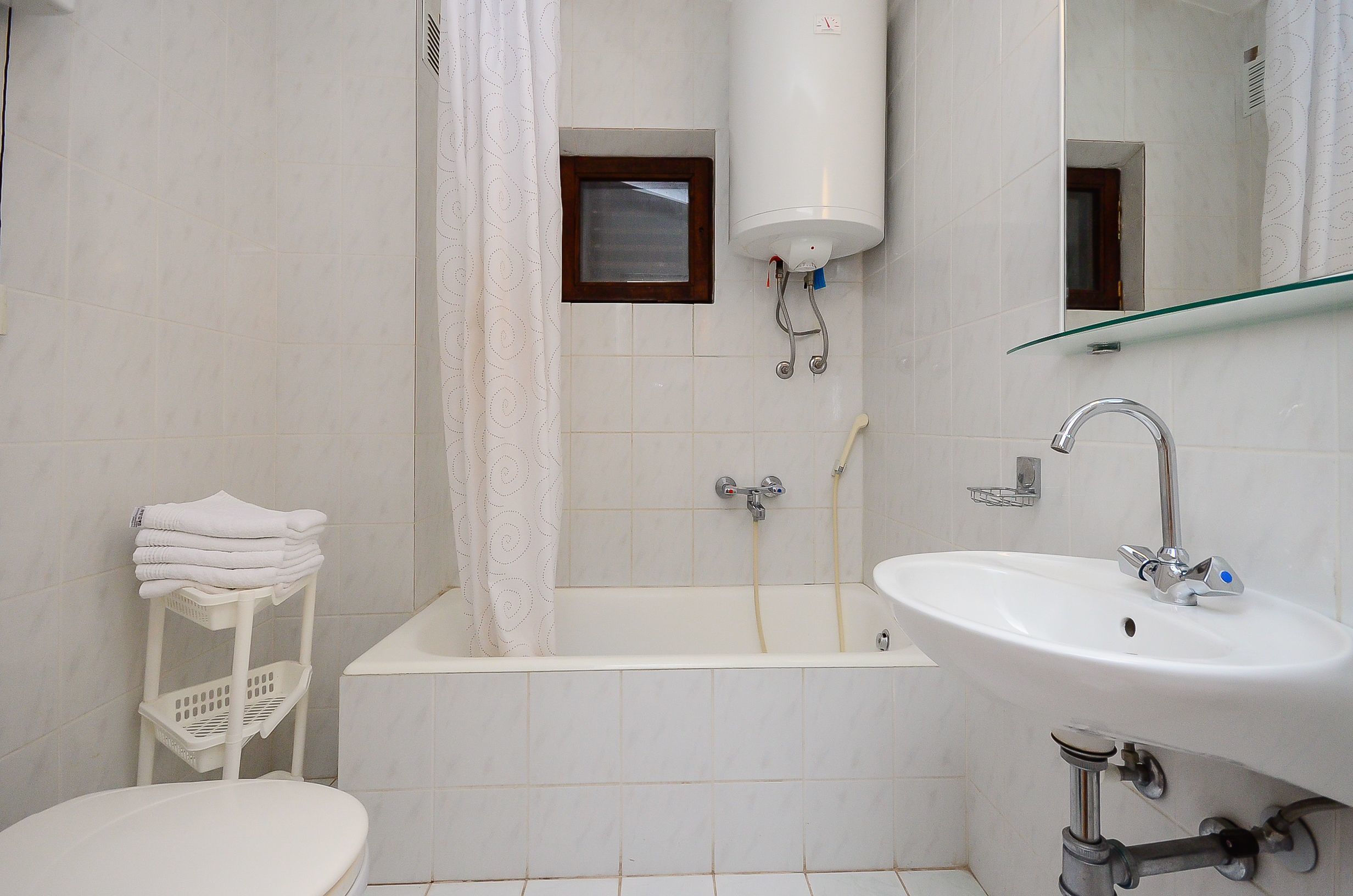 A bathroom with a white sink, a bathtub, a toilet, and a towel rack.