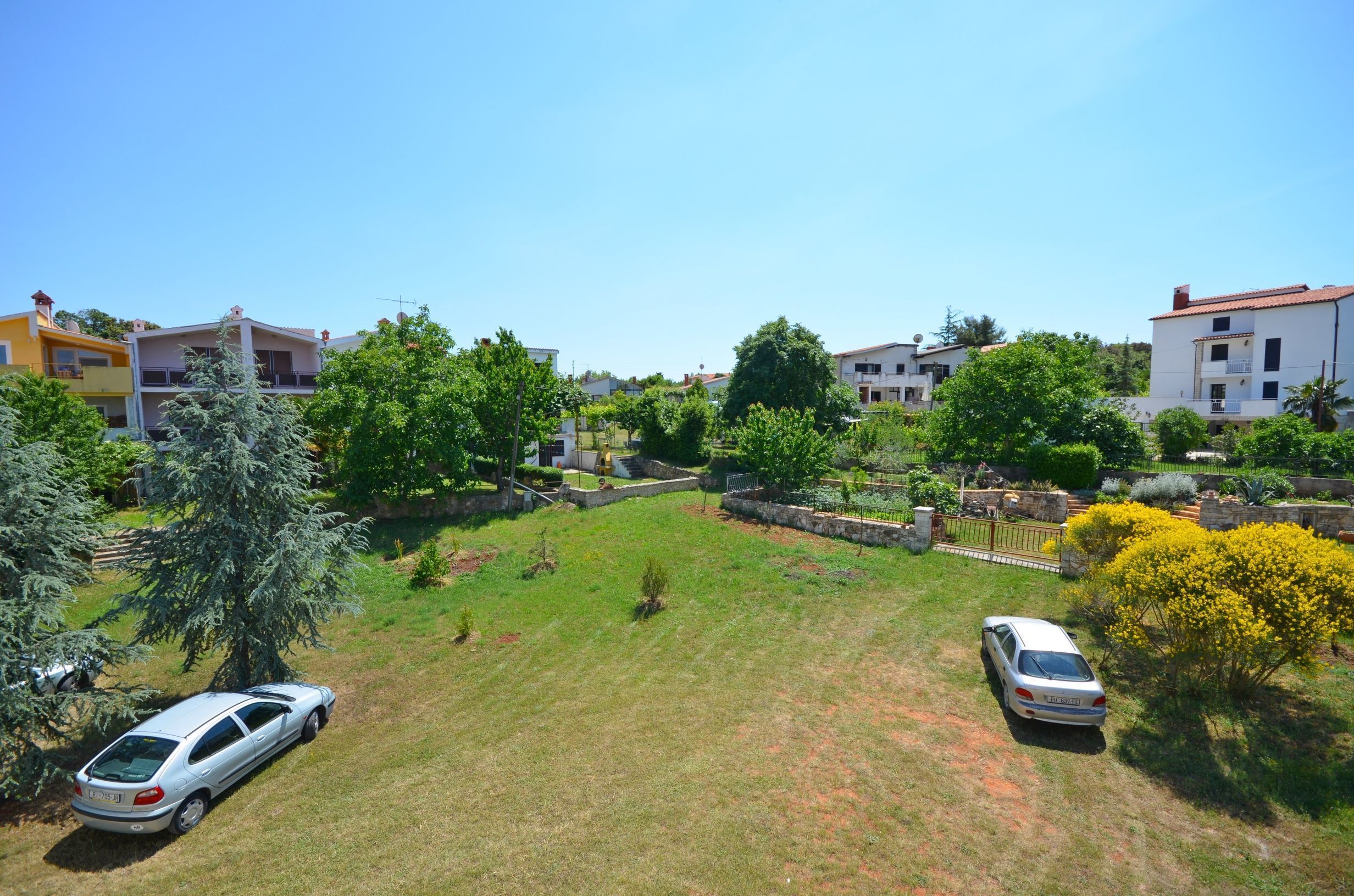 Un barrio residencial con casas, césped y coches aparcados.