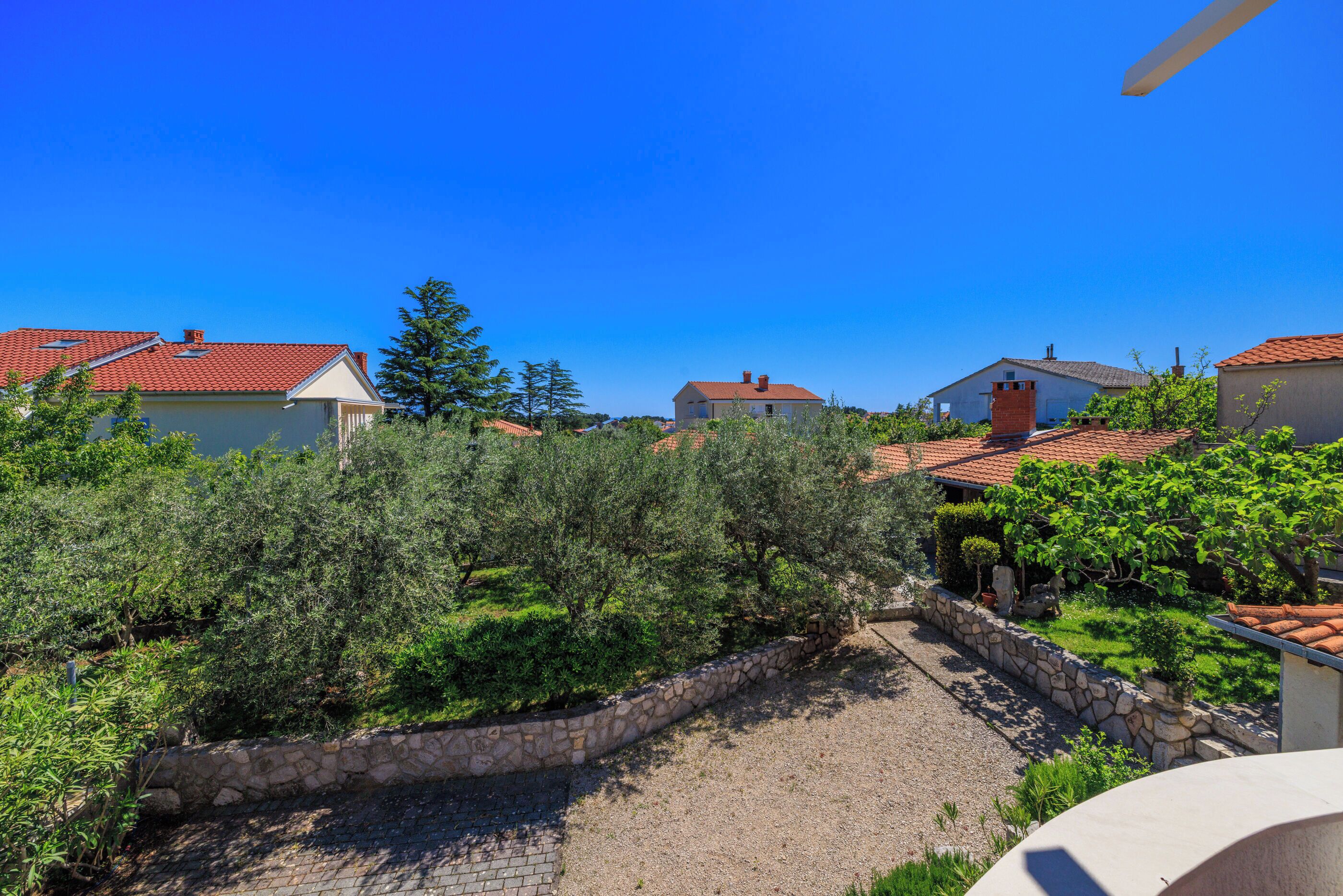 Un quartier résidentiel avec des maisons, un mur de pierre et un ciel bleu dégagé.