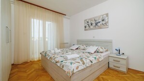 A bedroom with a wooden bed, a nightstand, a lamp, and a painting on the wall. - Apartments Ljubica (Kampor)