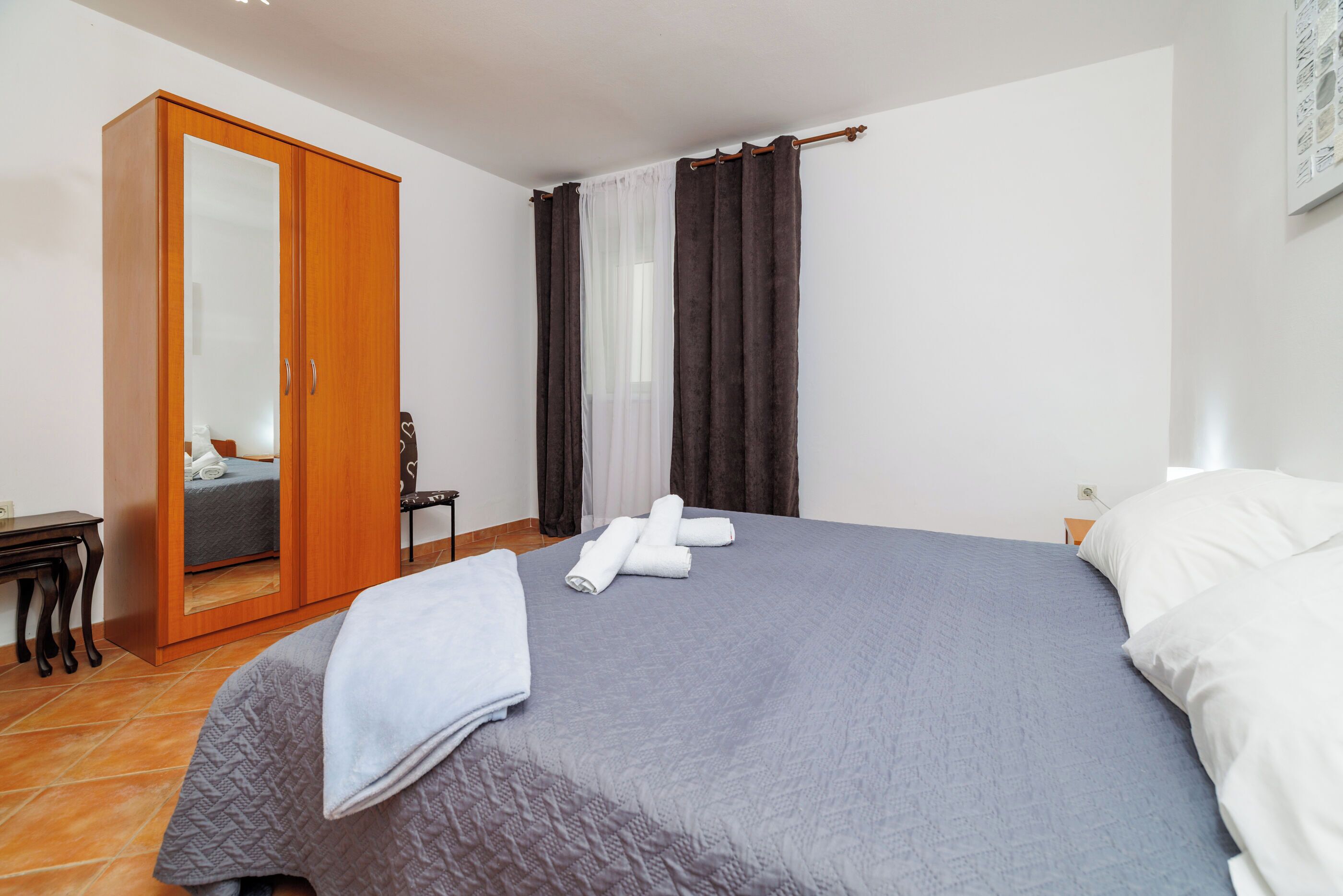 A bedroom with a bed, a wardrobe, a chair, and a desk.