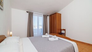 Ett hotellrum med en stor säng, en garderob i trä, en stol och ett fönster med gardiner.