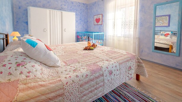 Quarto com cama, berço, guarda-roupa e janela com cortinas.