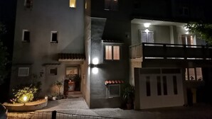 A modern two-story building with a balcony, a small entrance, and potted plants in the foreground. - Apartment Sanja (Rab)