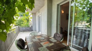 A dining area with a table set for two, surrounded by chairs, and a glass door leading to an outdoor space. - Apartment Sanja (Rab)