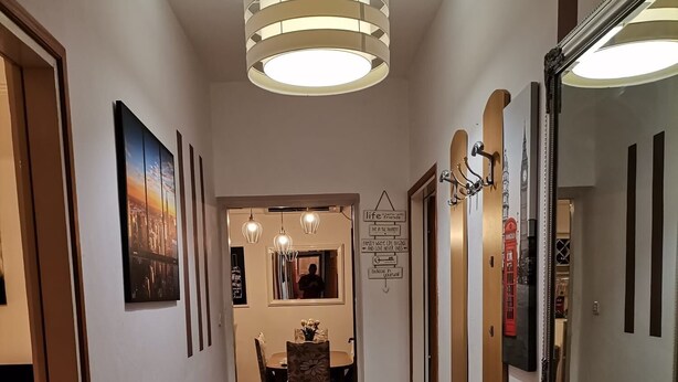 A hallway with a bench, a dining area with a table and chairs, and a large mirror on the right wall. - Apartment Sanja (Rab)
