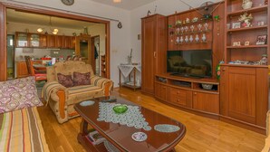 A living room with a sofa, coffee table, TV, wooden cabinets, and a dining area with chairs and a table. - Apartment Anica (Omis)