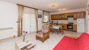 Un saló amb una butaca de fusta, un sofà vermell, una taula de centre de fusta i una zona de menjador amb taula i cadires.