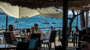 Un restaurant a la vora de la platja amb terrassa, amb vista al mar.