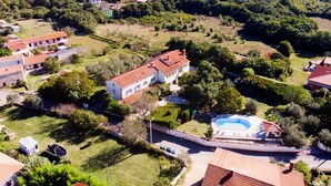 Eine großzügige Villa mit Swimmingpool, umgeben von üppiger Vegetation und weiteren Wohnhäusern.