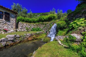 Ein Steinhaus mit einem kleinen Wasserfall und einem Bach.