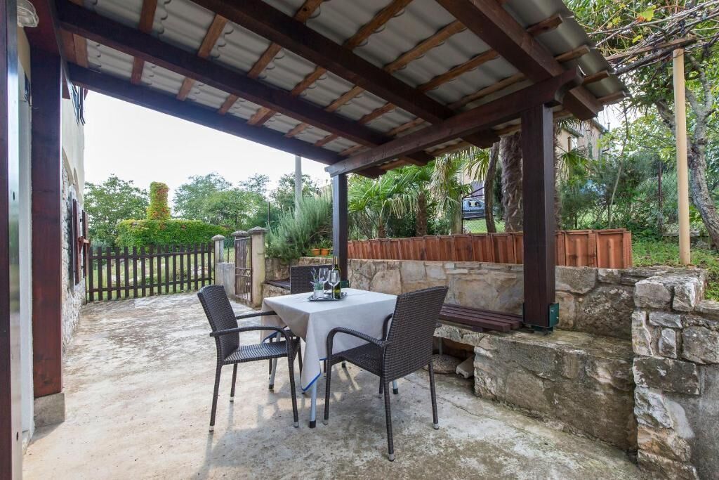 An outdoor patio with a covered seating area, stone walls, and a wooden fence.