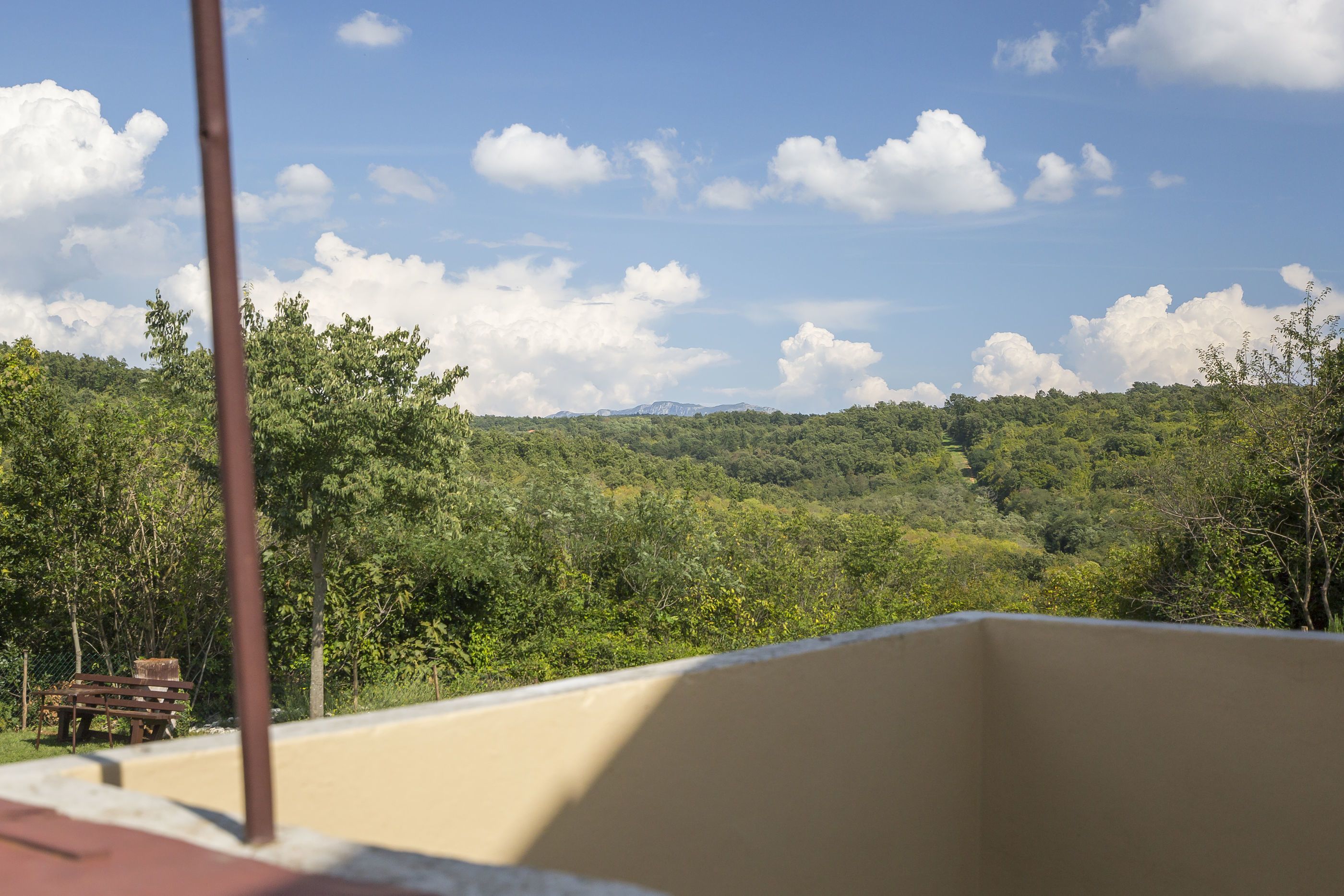 Ein Balkon mit Blick auf eine bewaldete Landschaft und ferne Berge.