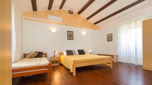 A bedroom with two wooden beds, a wooden ceiling, and a large window with sheer curtains. - House Dean (Labin)