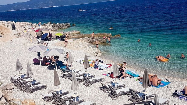 A beach with sun loungers, umbrellas, and people swimming. - House Dean (Labin)