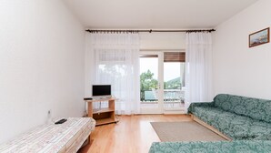 Una habitación con una cama, un escritorio con televisor, un sofá y vistas por una puerta.