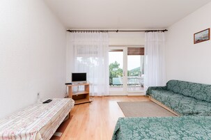 Una habitación con una cama, un escritorio con televisor, un sofá y vistas por una puerta.