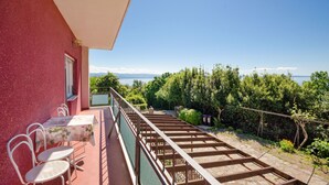 Un balcón con mesa y sillas, una pérgola de madera y vistas a árboles y montañas.