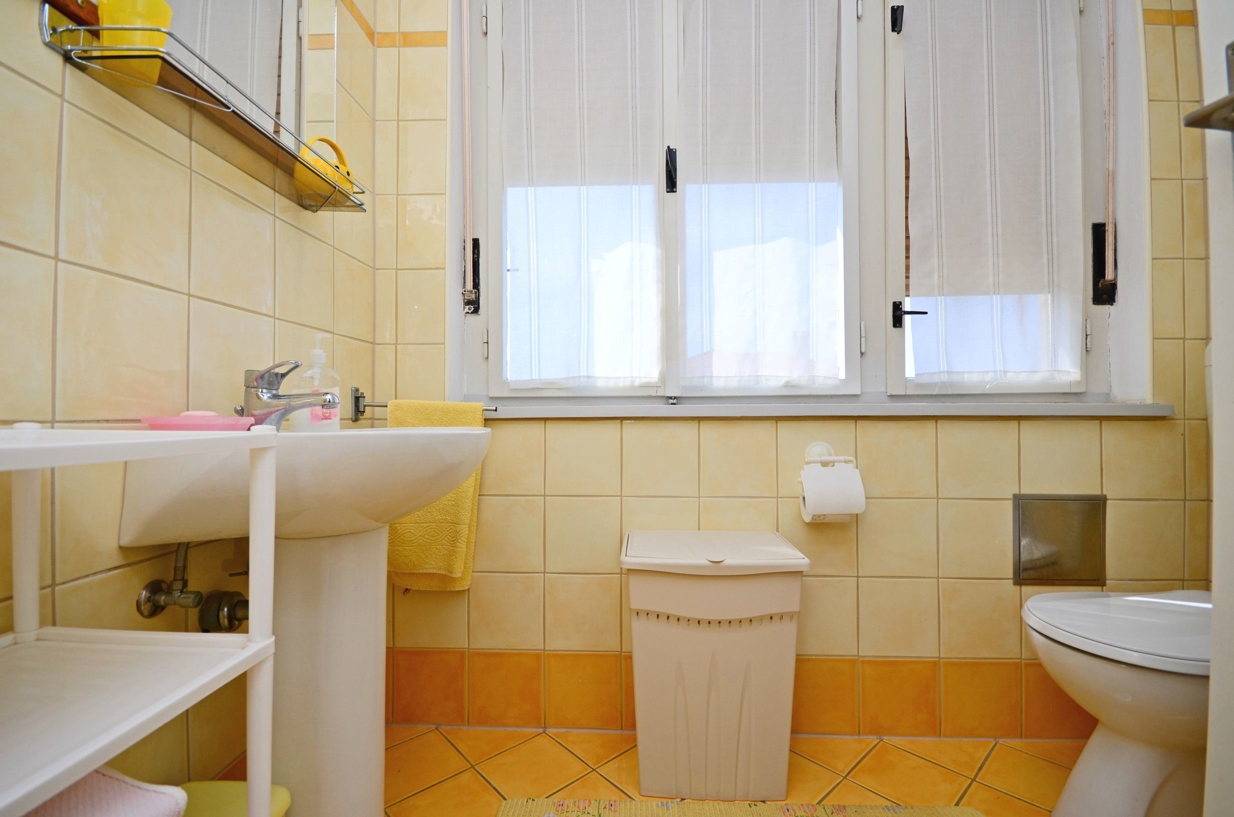 Een badkamer met een wastafel, toilet en raam.