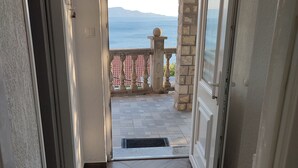 Un corridoio che conduce a un balcone con ringhiera in pietra e vista sul mare.