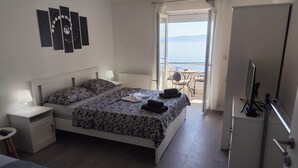 Una camera da letto con un letto, comodini, una scrivania, una sedia e un balcone con vista.