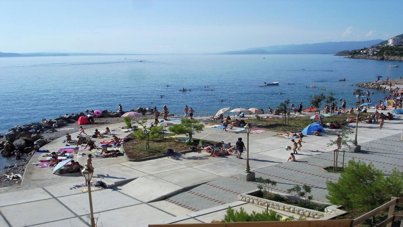 Une zone de plage où les gens se prélassent au soleil, nagent et s’amusent.