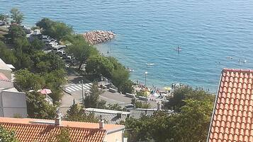 Une zone résidentielle côtière avec des maisons, une digue rocheuse et une plage où les gens se baignent et prennent des bains de soleil.