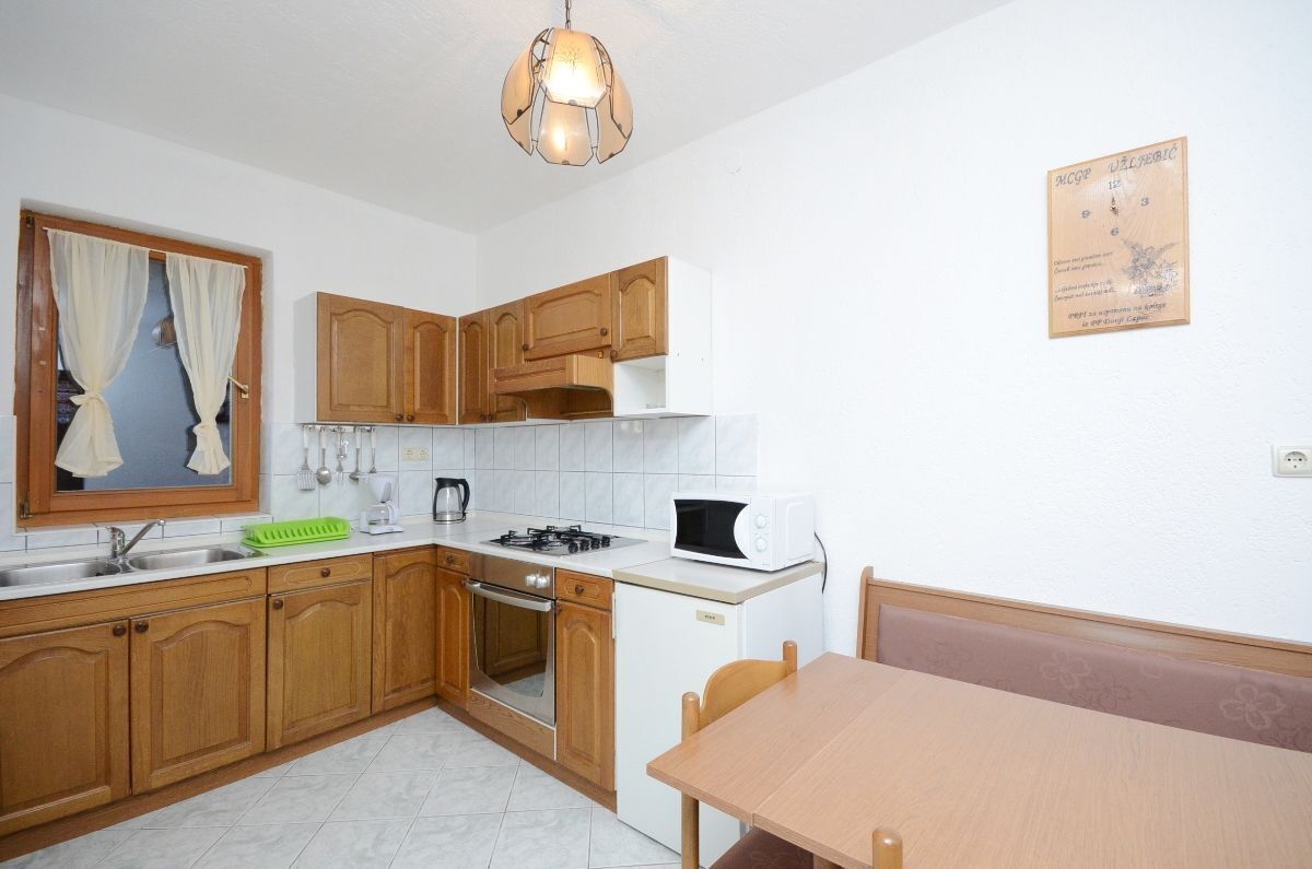 A kitchen with wooden cabinets, a stove, a microwave, and a dining table.