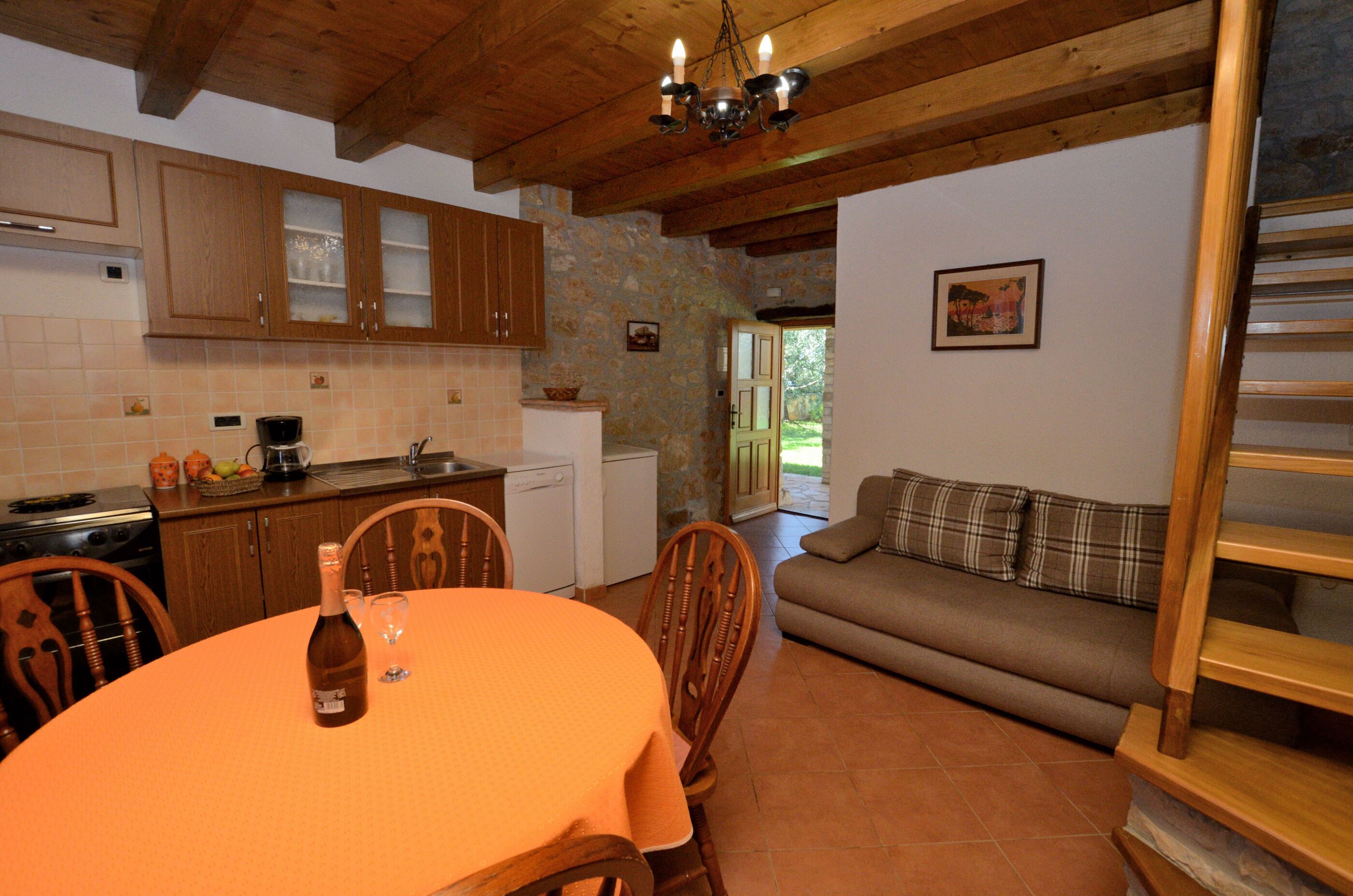 A kitchen with wooden cabinets, a dining table with a wine bottle, and a sofa in a living area.