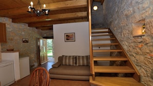 A rustic interior with a wooden staircase, stone walls, a sofa, and a dining area. - House Mariano (Lasici)