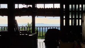 Una habitación con suelo de madera, una mesa y una silla. Se ve una vista de montañas a través de las ventanas.