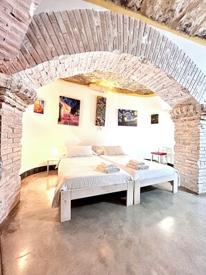 Ein Schlafzimmer mit Ziegelgewölbe, einem Bett, zwei Nachttischen und drei Bildern an der Wand.
