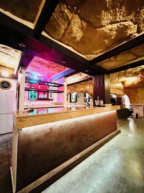 Ein Empfangsbereich mit Theke, Barbereich und Steinwand.