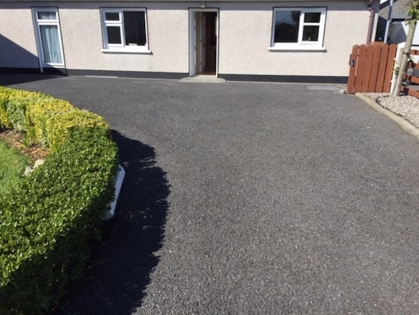 A residential driveway leading to a house with a door and windows.