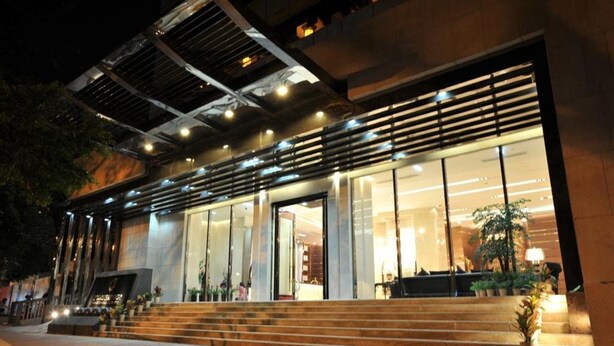 A modern building with large glass windows, a staircase leading to the entrance, and outdoor lighting. - Guangzhou Easun Guotai Hotel (Guangzhou)