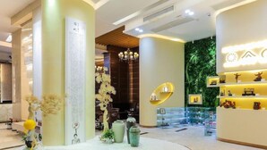 A modern lobby with a central round display, a chandelier, and a green wall with shelves. - Guangzhou Easun Guotai Hotel (Guangzhou)
