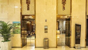 A hotel lobby with two elevators, a trash bin, and a potted plant. - Guangzhou Easun Guotai Hotel (Guangzhou)