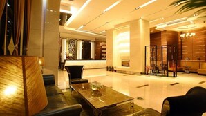 A modern lobby with a reception desk, seating area, and a large mirror. - Guangzhou Easun Guotai Hotel (Guangzhou)