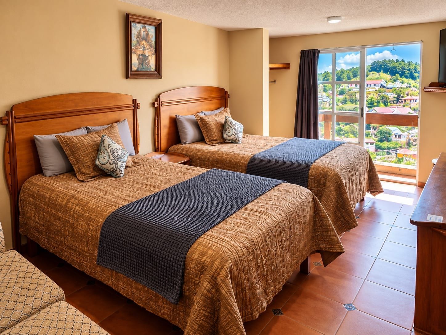 A hotel room with two beds, a balcony with a view, and a painting on the wall.