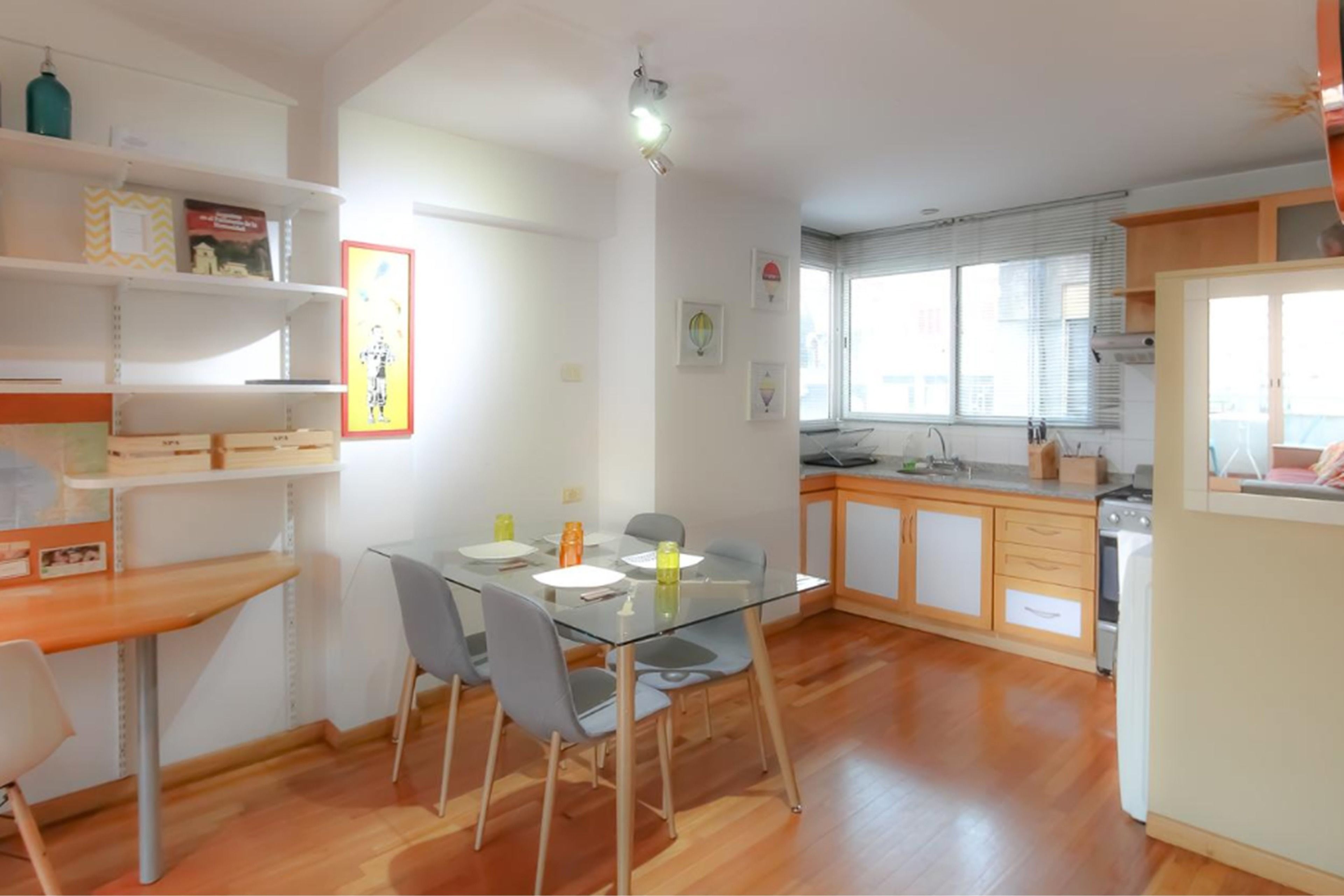 Una cocina moderna con armarios de madera, horno empotrado y ventana con persianas.